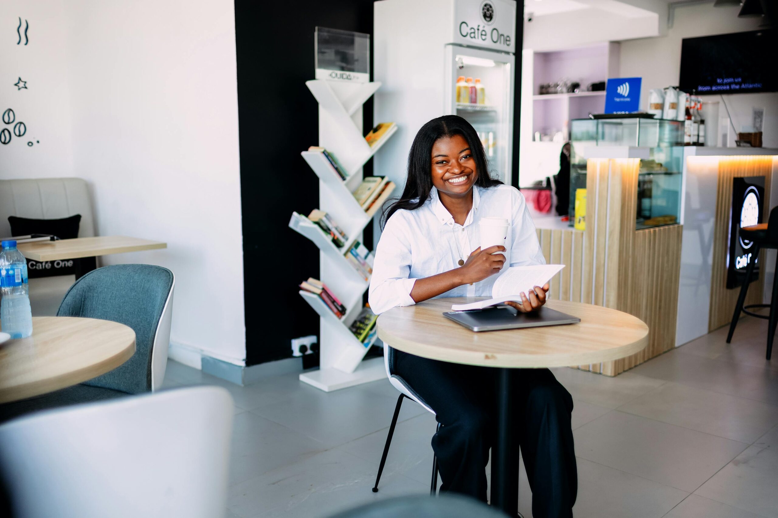 Home Smiling woman enjoys a book and coffee in a modern Lagos café.